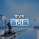돌리줌 썸네일: 아래쪽 레일 위에 돌리에 올린 영화 카메라가 있고 가운데·위로 글자를 올릴 푸른 여백이 넓은 모습